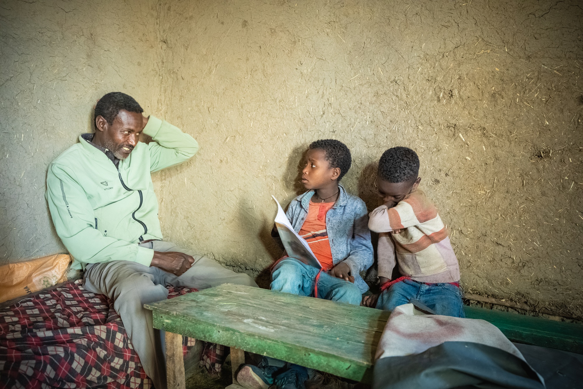 Un père aide ses deux enfants à faire leurs devoirs.